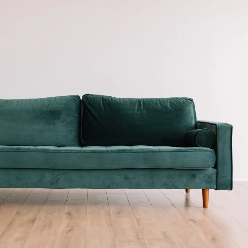 木製脚と深緑のベロア生地が特徴的な3人掛けソファ